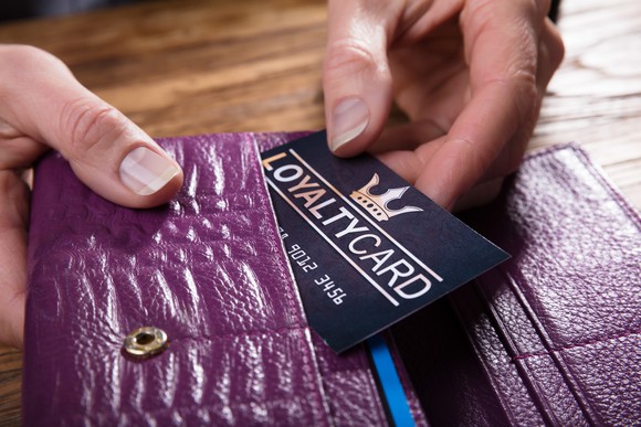 Hands pulling a generic loyalty card out of a purple wallet