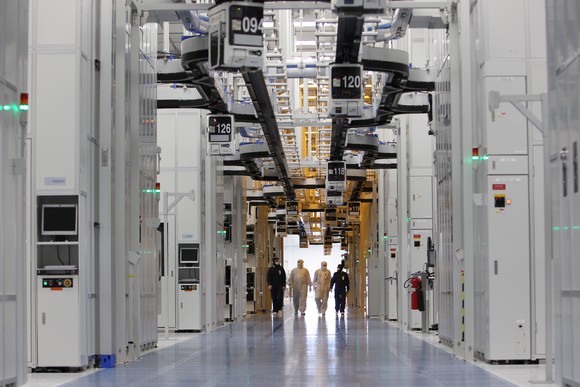 Four employees walking down a long corridor in a Texas Instruments' manufacturing facility.