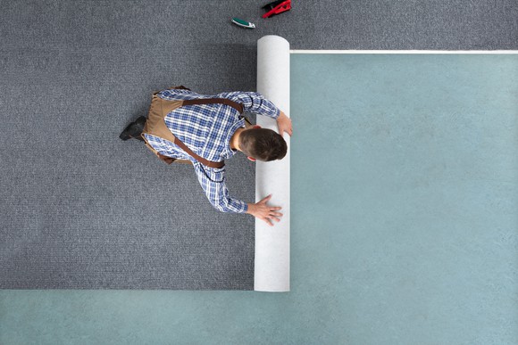 Man installing carpet on floor