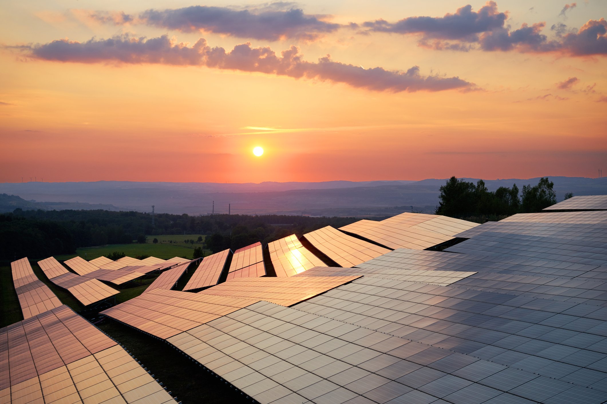 Solar panels in a field under a sunset