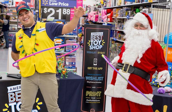 A Walmart employee and Santa standing at a holiday display 