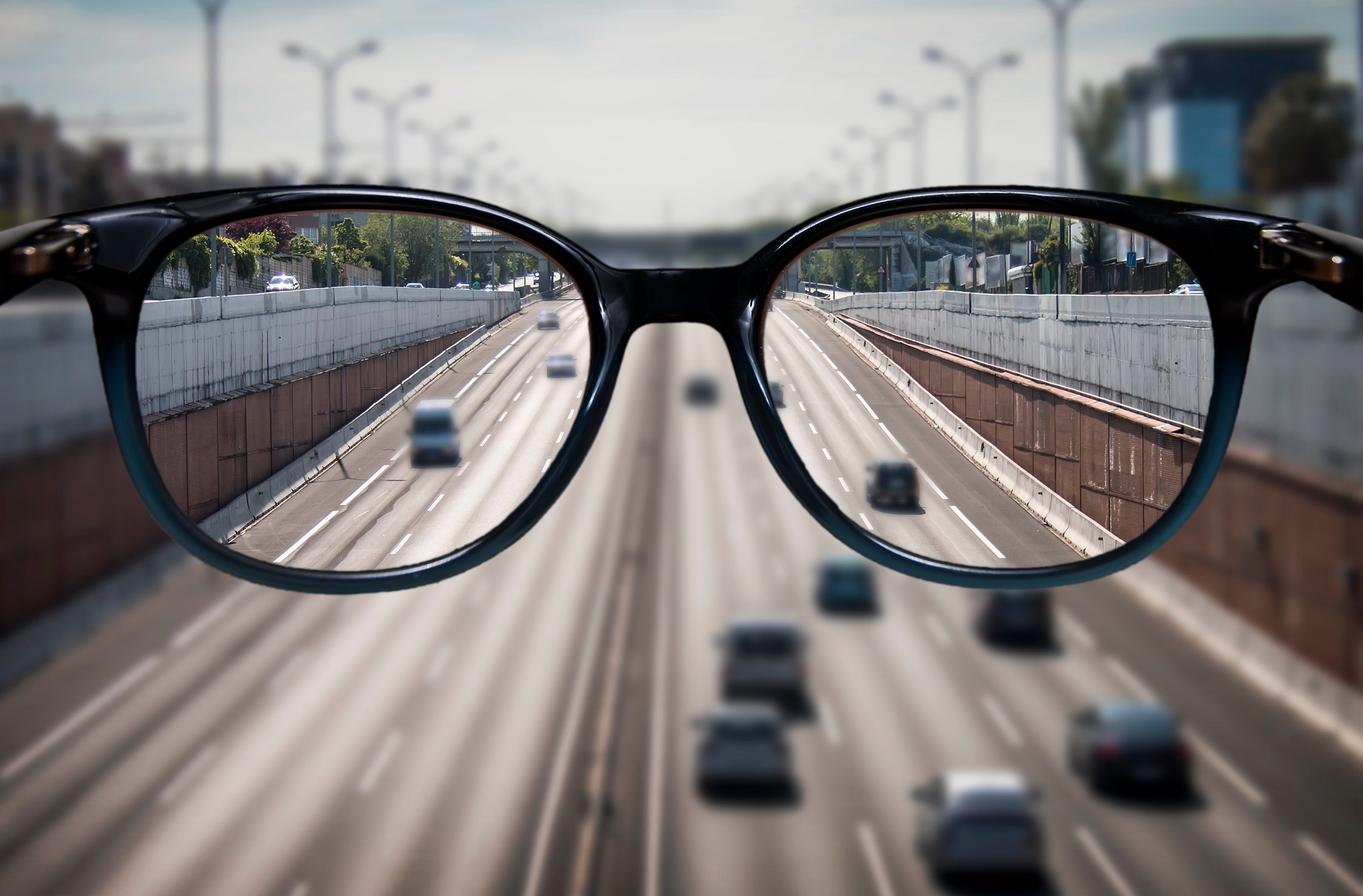 A pair of glasses in front of a multi-lane highway.