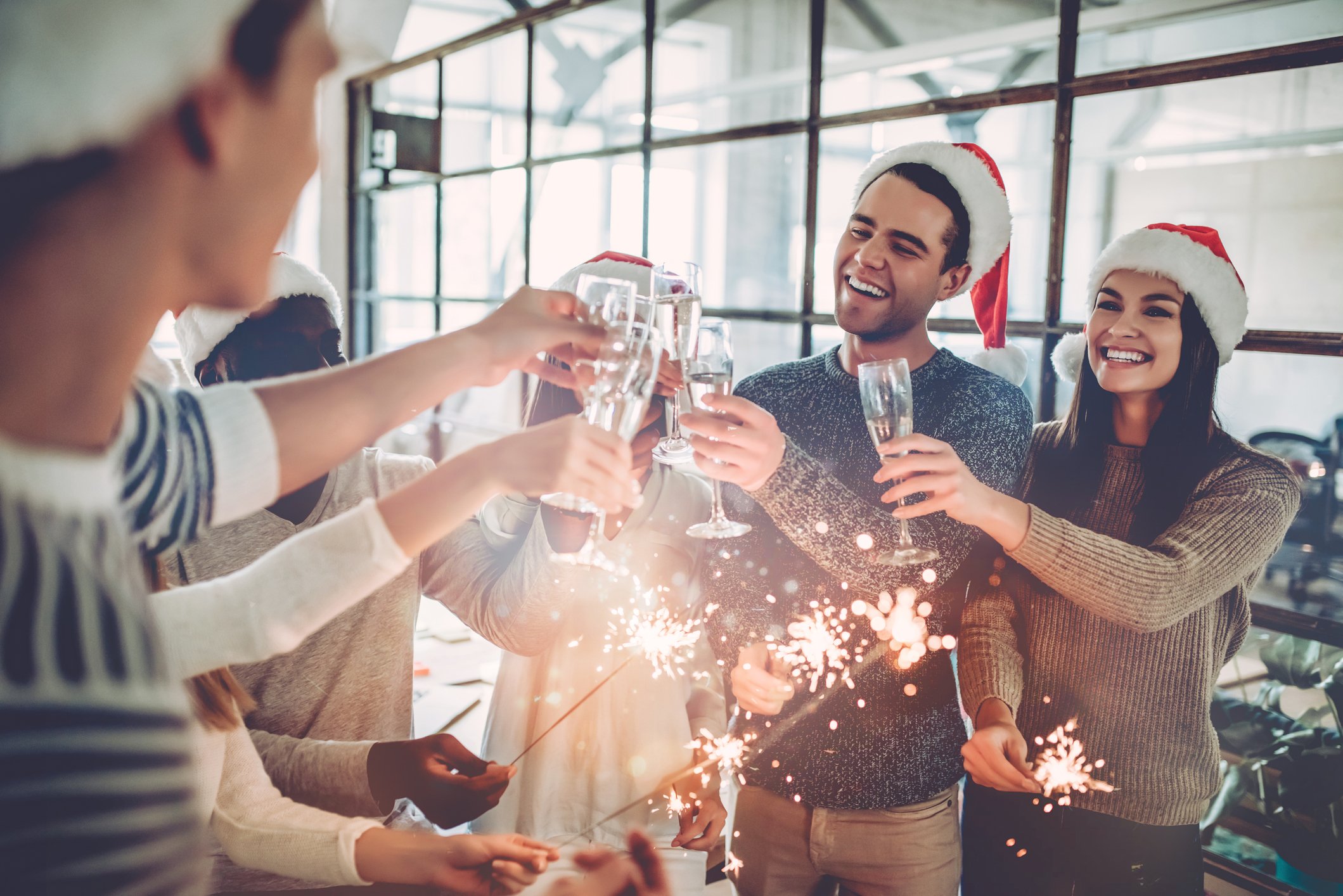 Group of people wearing Santa hats and clinking glasses