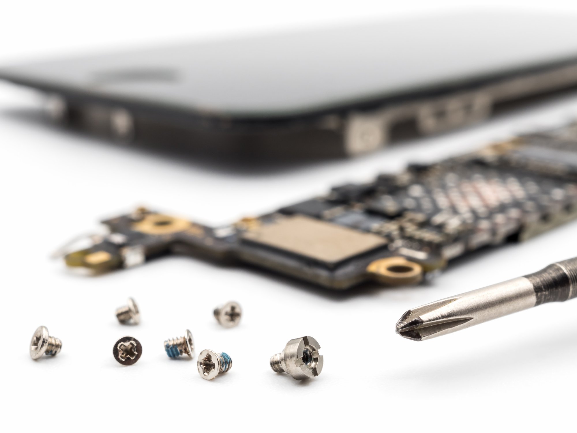 Close-up shot of a disassembled smartphone, surrounded by screws and components.