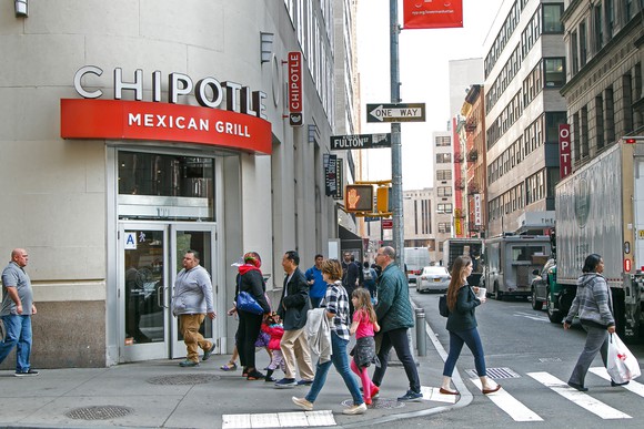 People cross a crosswalk outside a Chipotle Mexican Grill. 