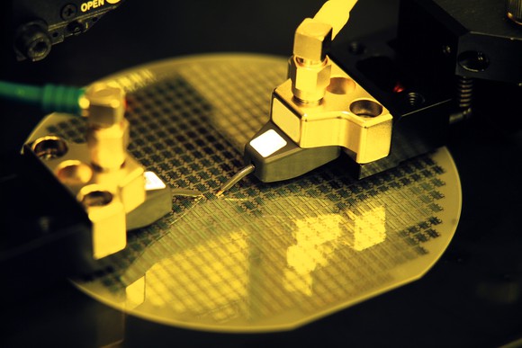 An unfinished semiconductor wafer is being procesed by several robotic tools.