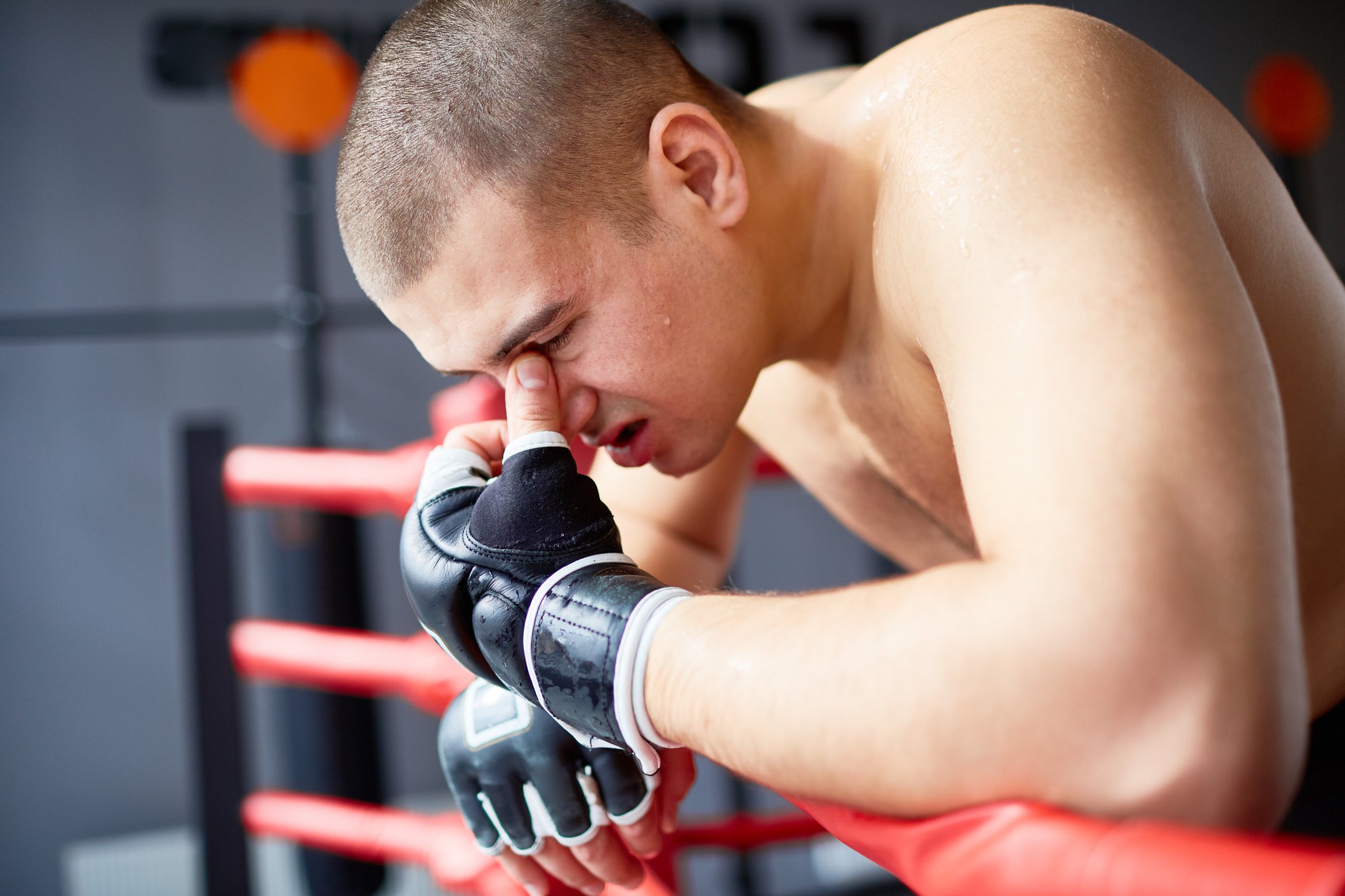 Defeated MMA fighter sits against the ropes.