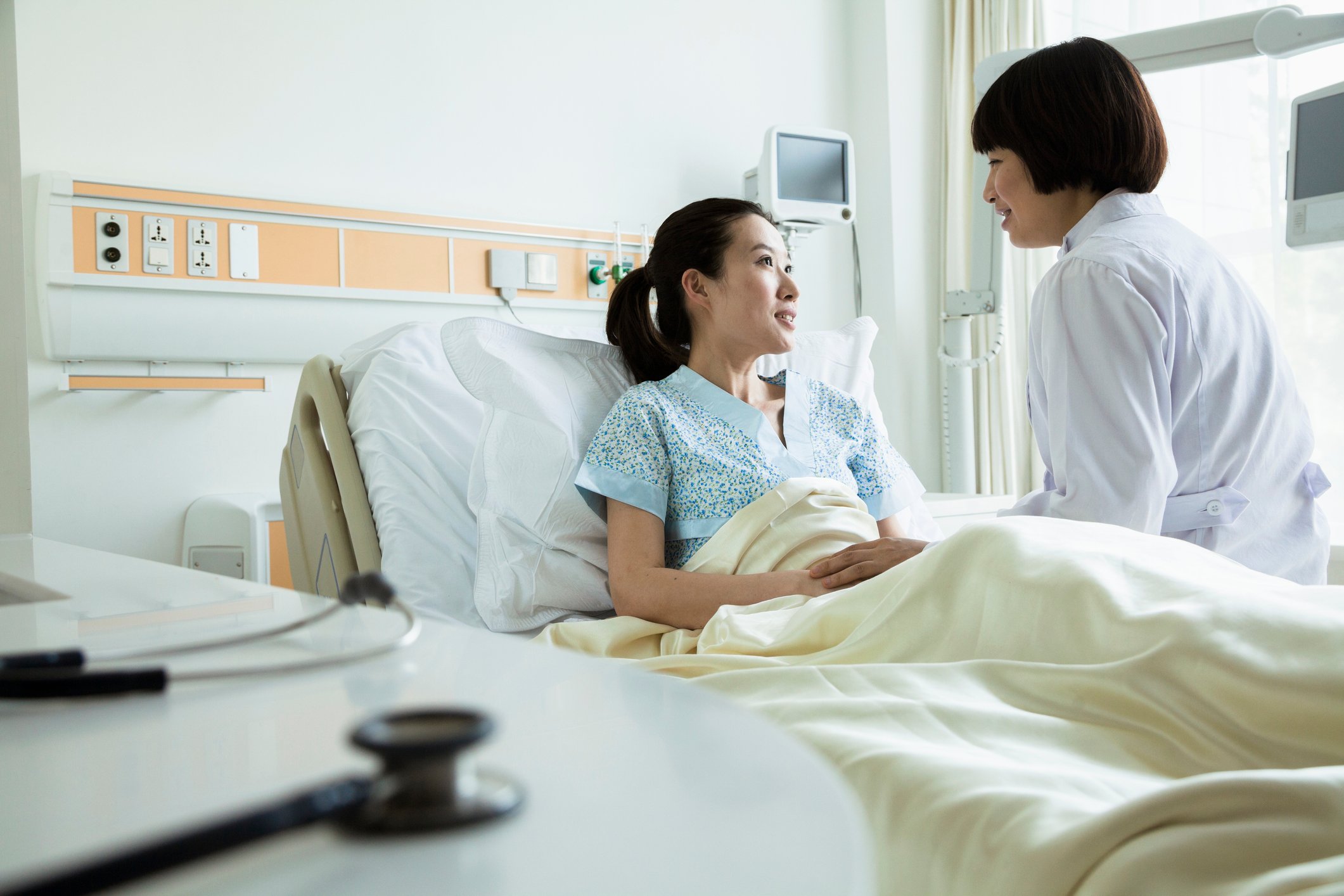 A patient in a hospital bed with a doctor at her bedside