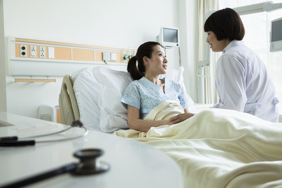 A patient in a hospital bed with a doctor at her bedside