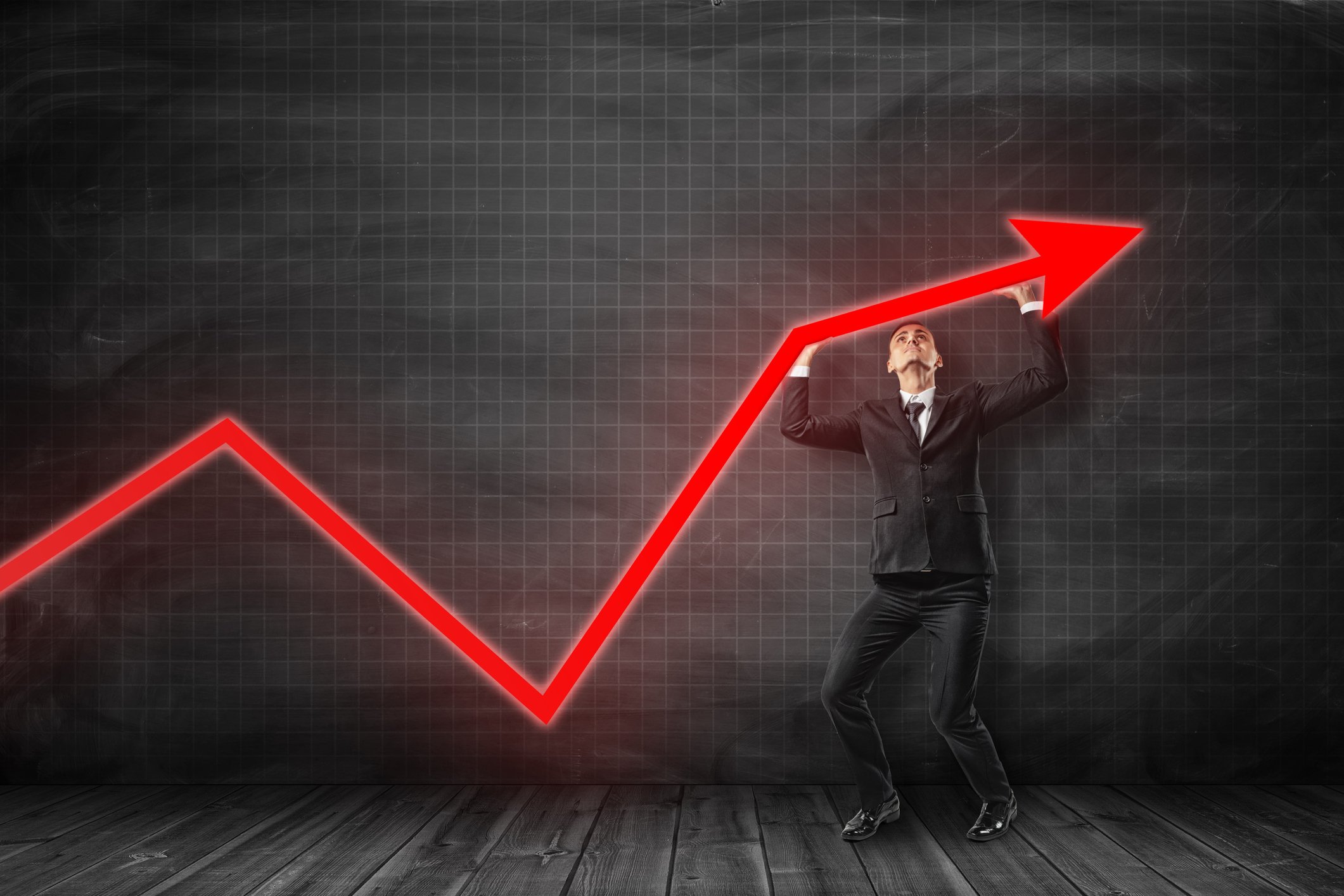 Businessman holding up a red arrow that's pointing upwards. 