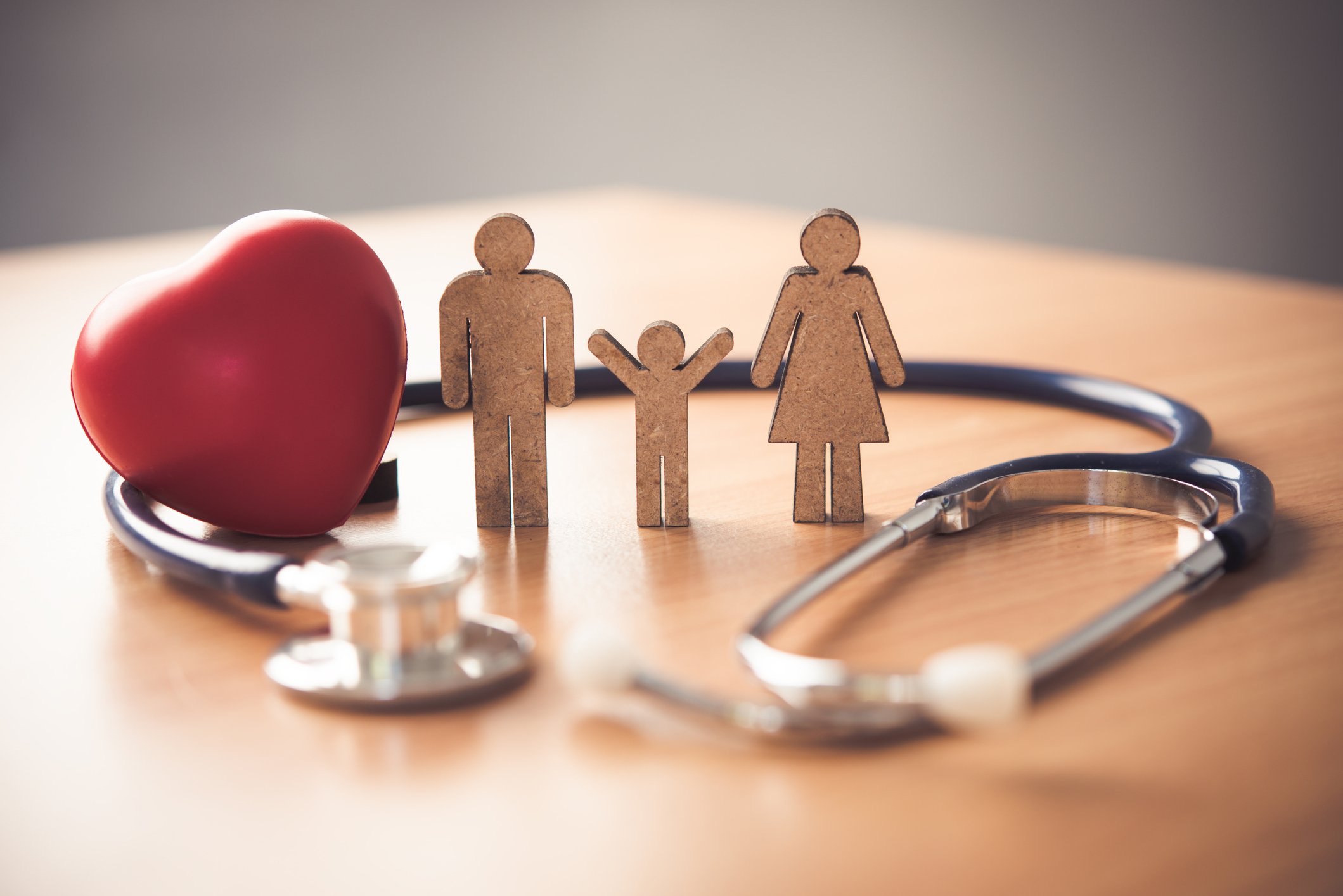 A stethoscope, a heart icon, and miniature figurines of a man, woman, and child.