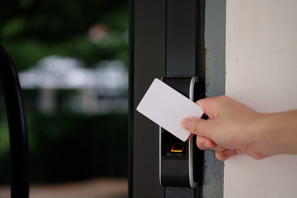 A hand holds a key card to an electronic door lock.