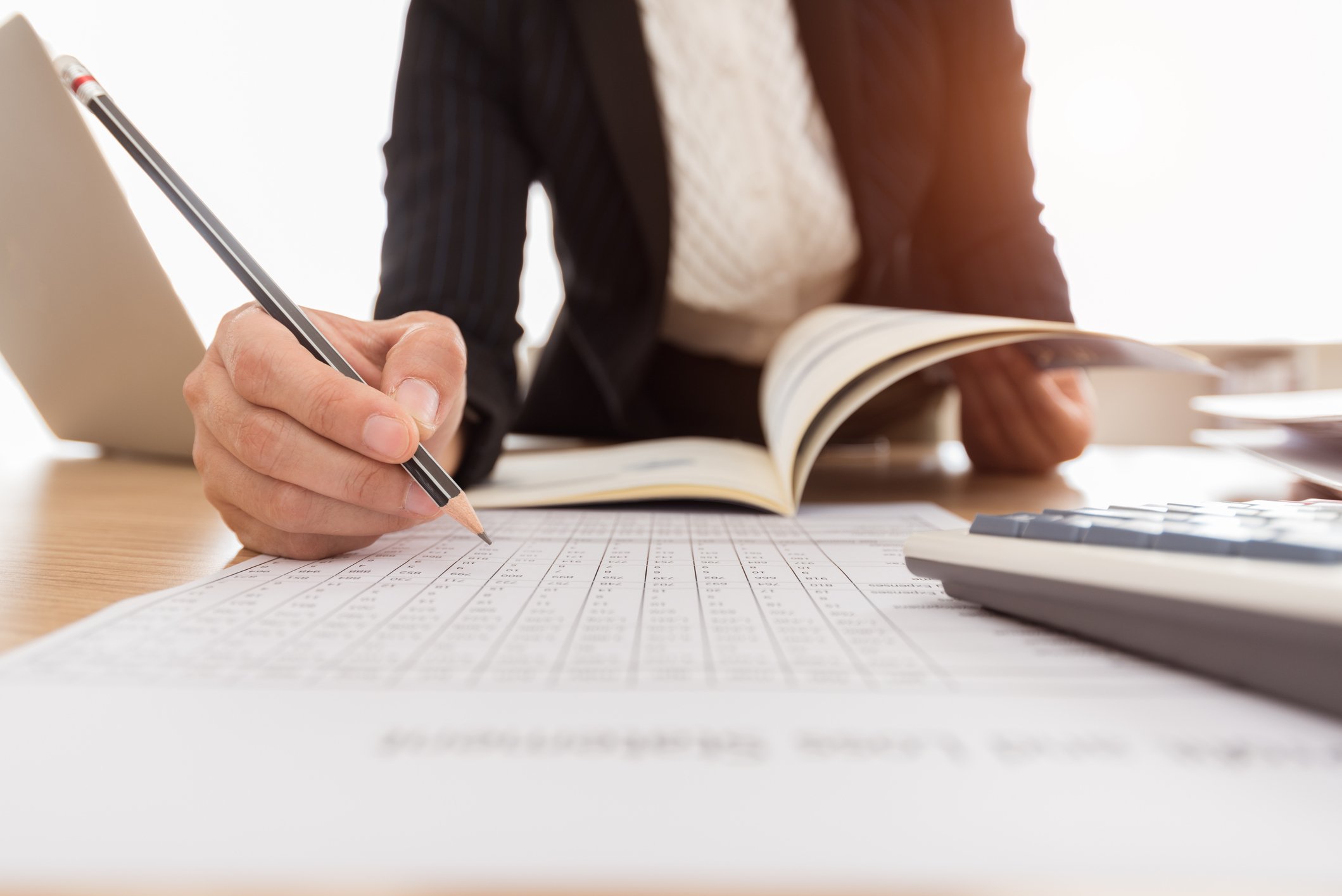 Accountant working with a pencil on a ledger of numbers.