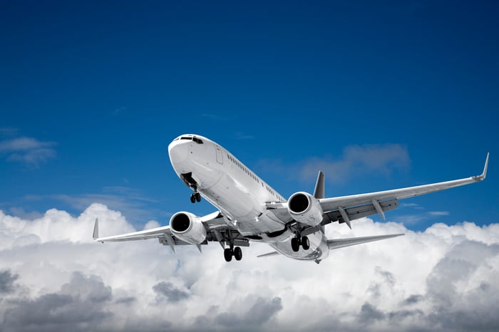 An airplane in flight with blue sky and white clouds in the background