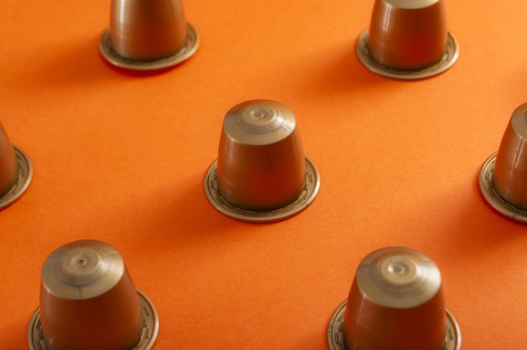 Bronze-colored coffee pods turned upside down on an orange surface.
