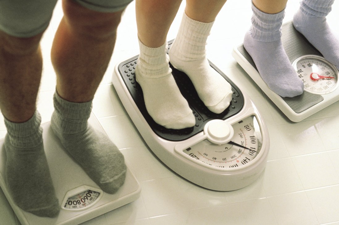 Image of three people in socks standing on scales weighing themselves