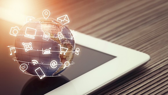 Globe with online shopping images is atop a tablet