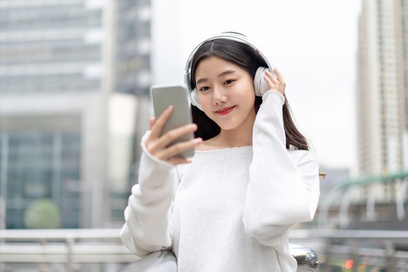 A young woman listens to music on her smartphone.