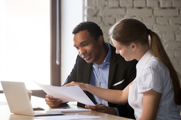 Female salesperson consulting with a male client about loan paperwork.