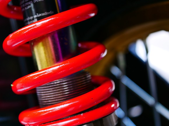 Close-up of a red coiled spring in a car engine's suspension system