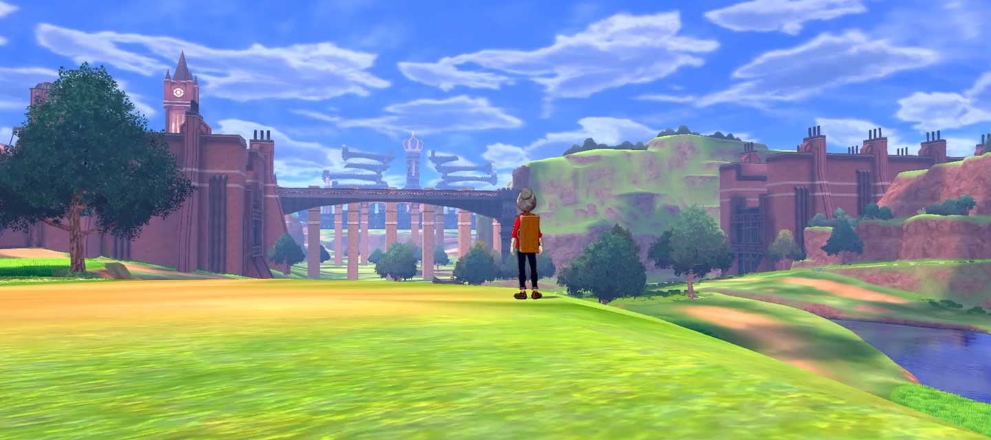 A player-character in the latest Pokemon game standing on a hill and looking at a bridge and castle in the distance.