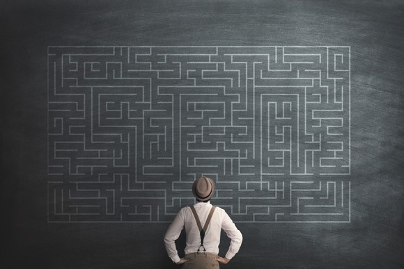 A man looks at an illustration of a massive maze.