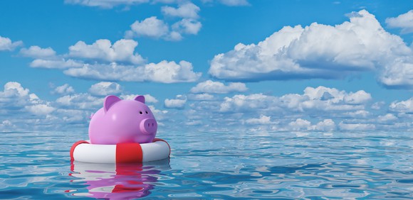 A pink piggy bank in a life buoy floating in the open ocean. 