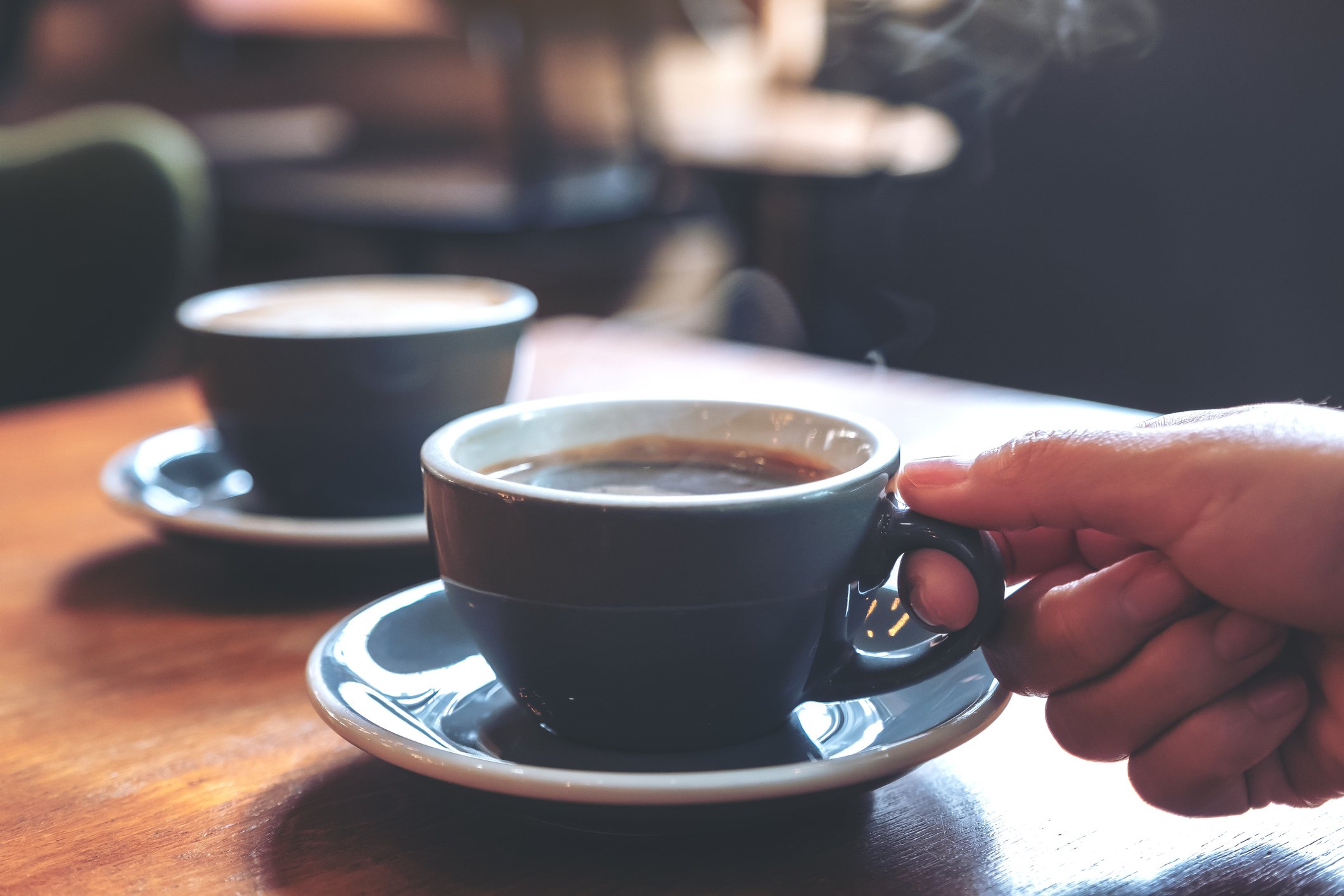 Steaming blue coffee cups on a wooden table.