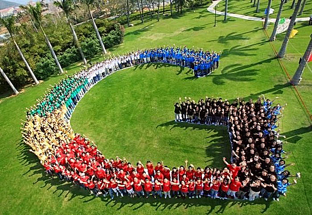 People in various colored shirts stand in the shape of Google's G logo