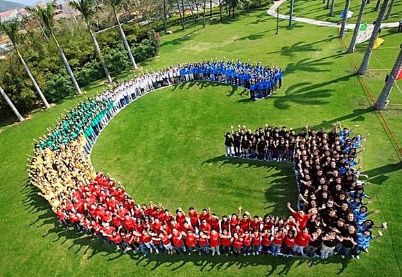 People in various colored shirts stand in the shape of Google's G logo