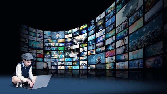 A young boy surrounded by a wall of video screens.