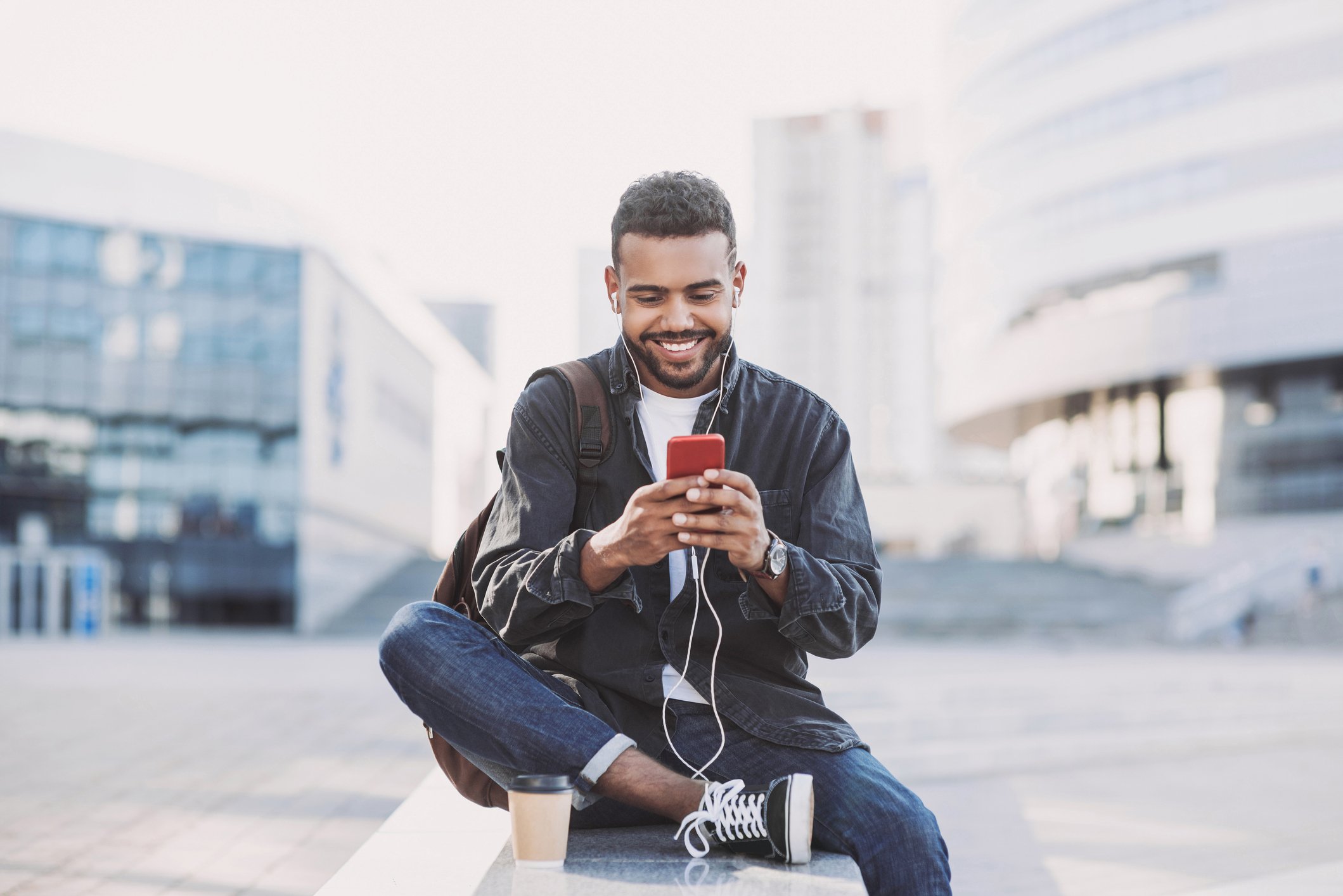 Man using a smartphone on a bench. 