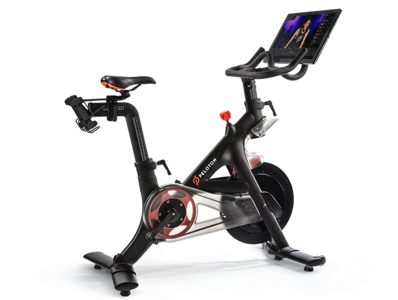 Stationary bike with Peloton logo, along with display showing exercise program.