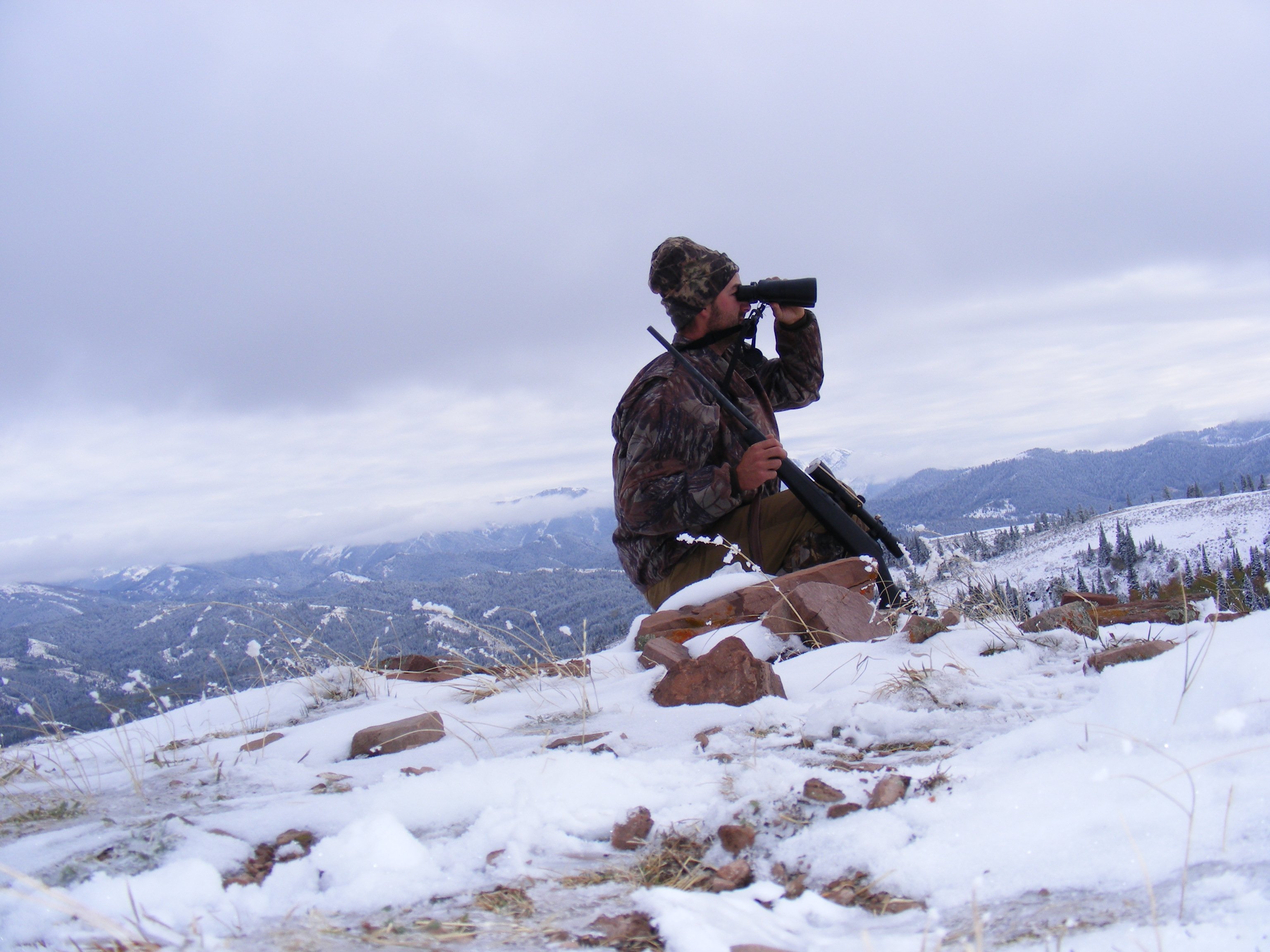 Man hunting on mountainside in winter.