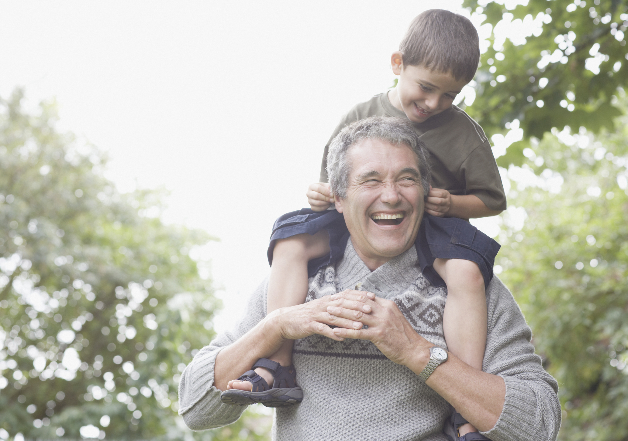 Smiling older man with boy sitting on his shoulders.
