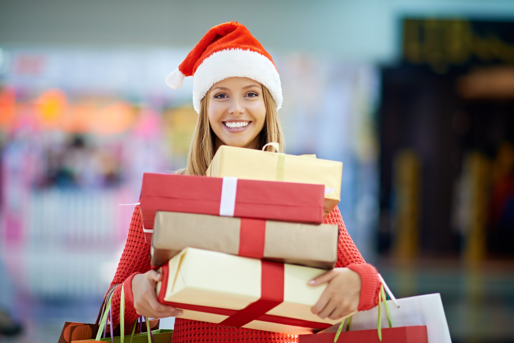 Smiling woman in a Santa hat, holding gift packages