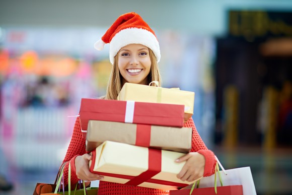 Smiling woman in a Santa hat, holding gift packages