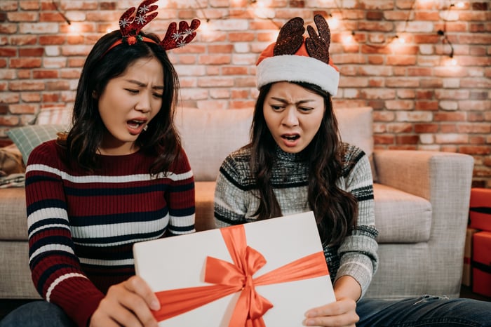 Two people look shocked opening a present. 