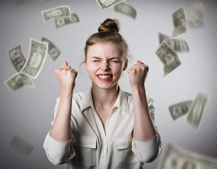 Smiling woman with money raining down upon her