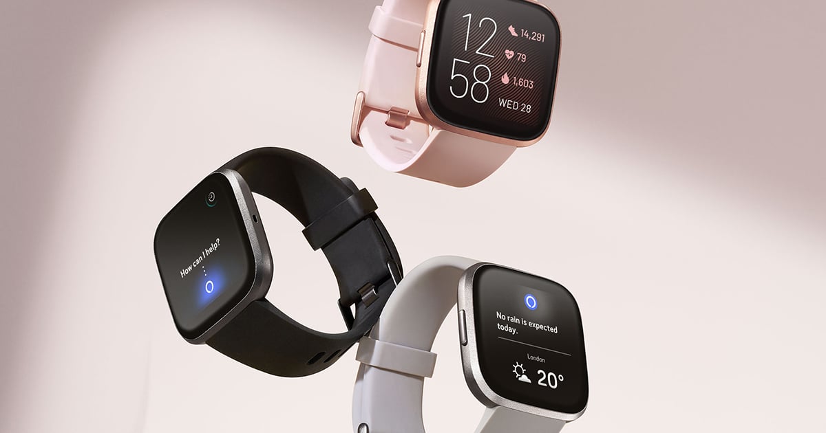 Three Fitbit wearable devices, one in pink, one in black, and one gray.