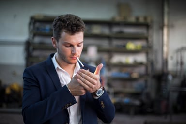 Man in blazer lighting a cigarette