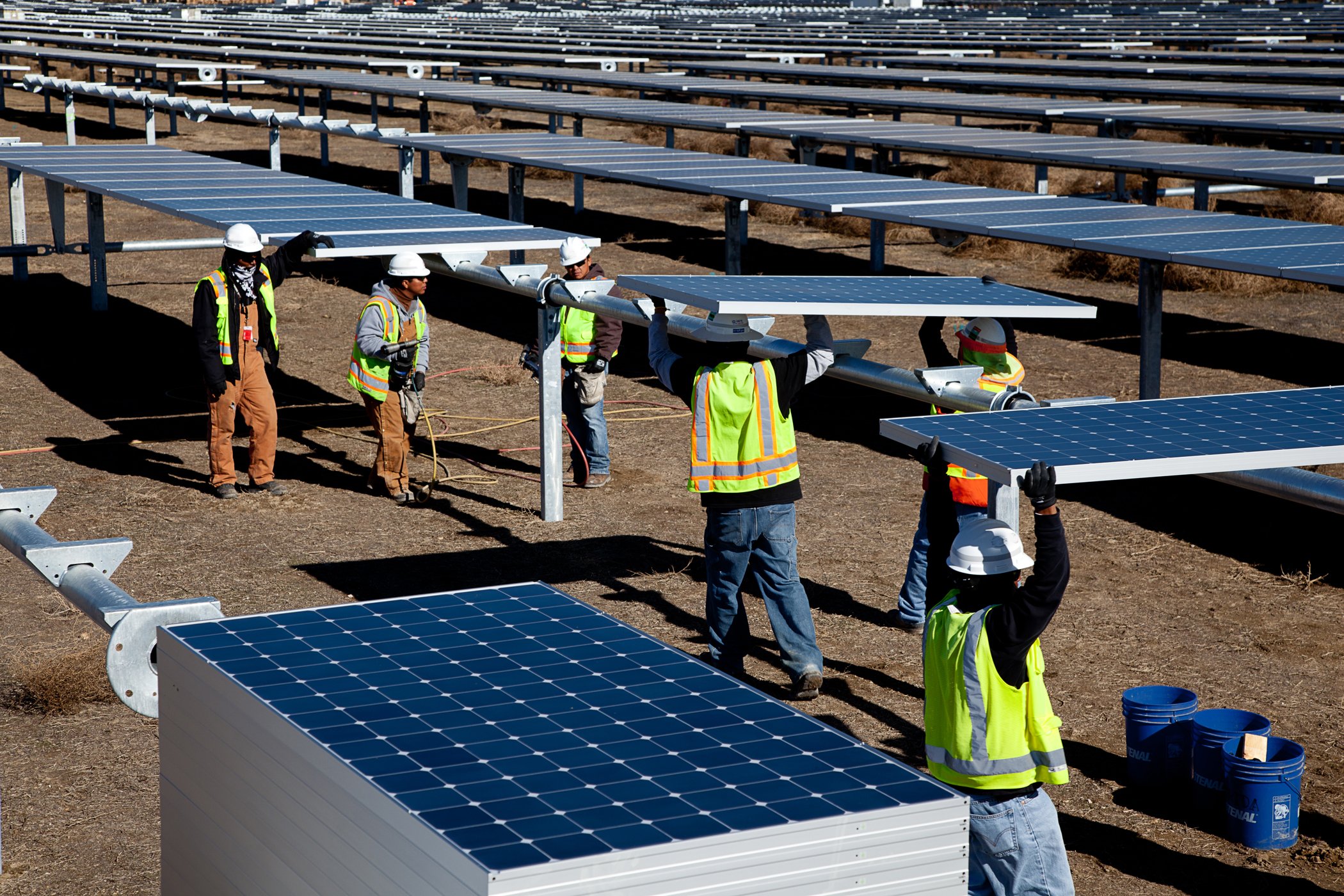 Workers installing solar panels at solar farm. 