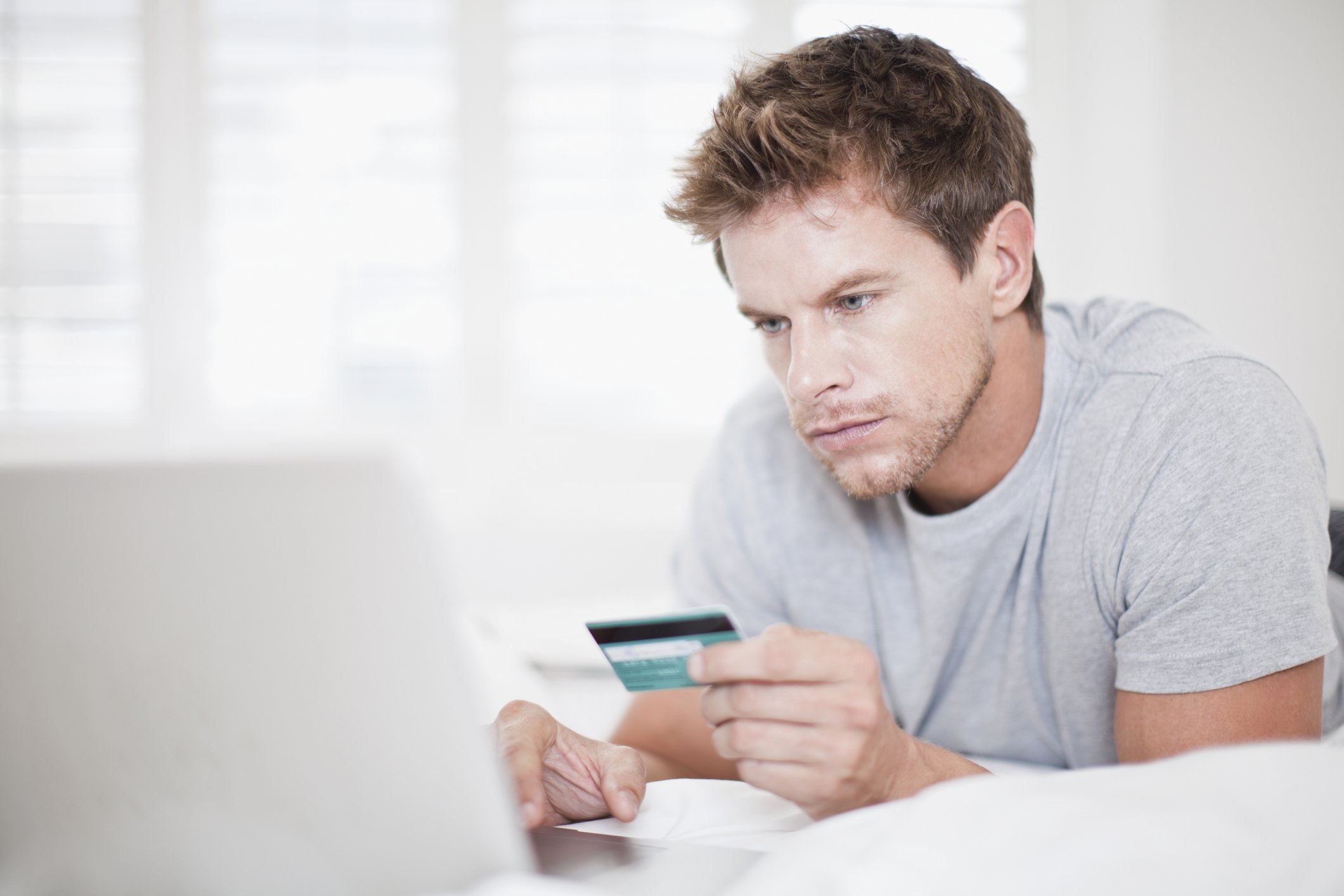 Man holding credit card and looking at laptop