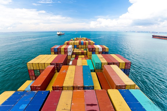 A cargo ship stacked with colorful containers entering a port.