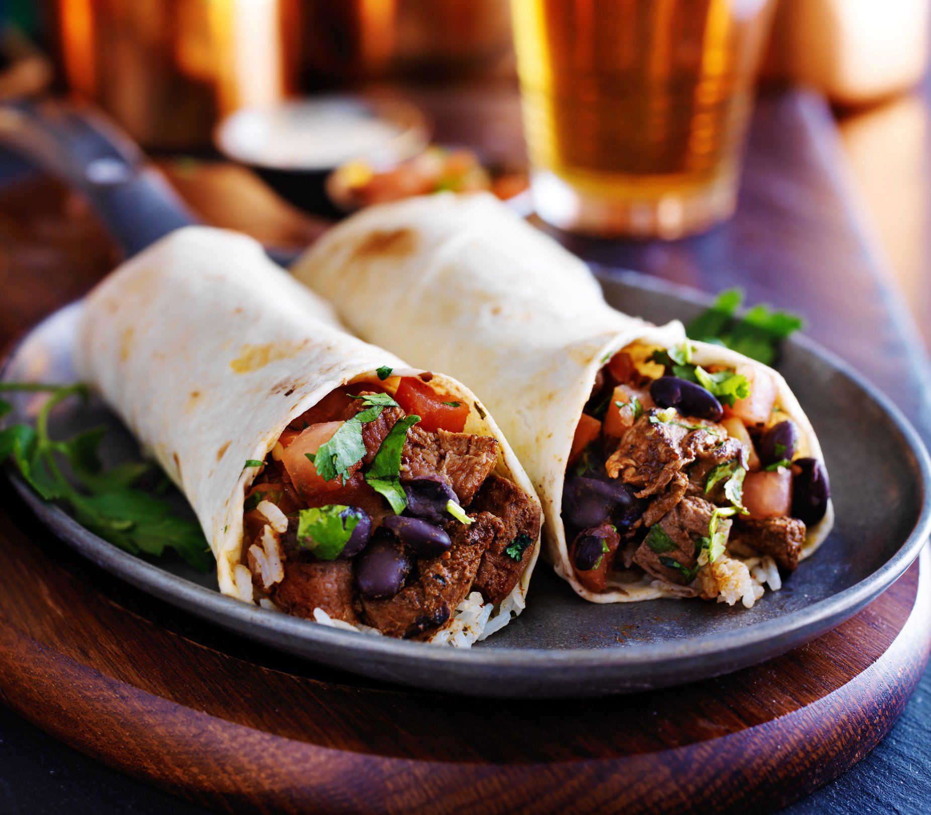 Two steak burritos on a plate.