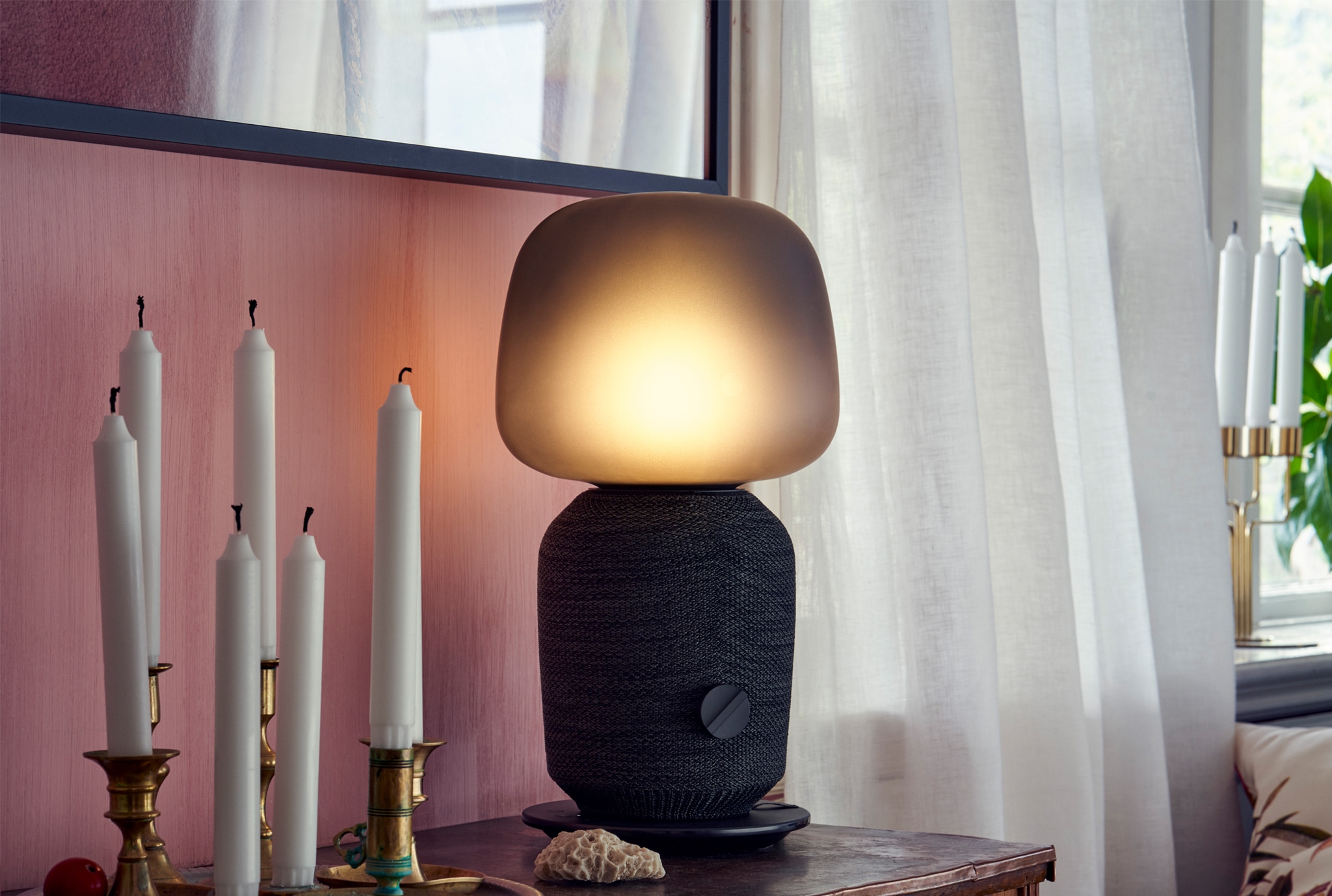 The SYMFOSONIK speaker lamp on a small table with several unlit candles.