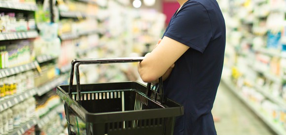 Female customer with a shopping basket standing in a pharmacy aisle