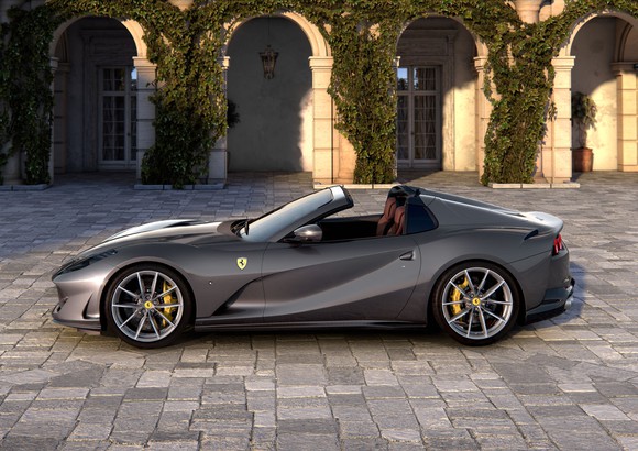 A gray Ferrari convertible parked in a cobblestone driveway.