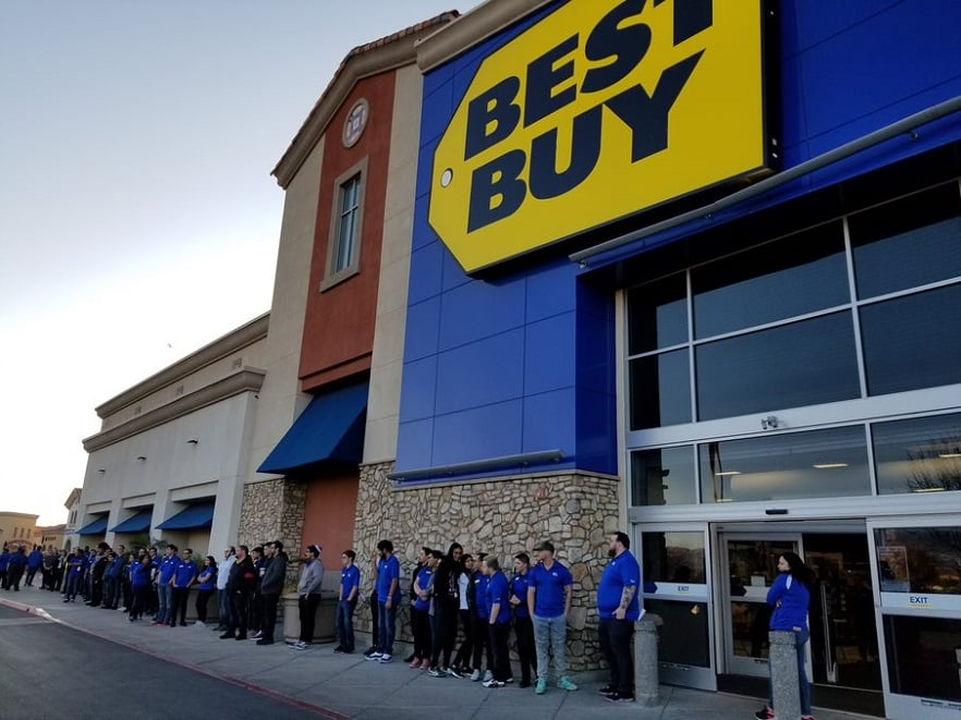 A line of people gather outside a Best Buy store.
