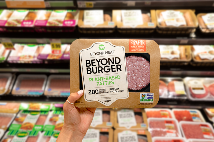 A hand holding Beyond Burger package in a grocery store